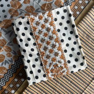 Unstitched Mal Mal cotton suit set with black polka dots, mustard floral embroidery, and matching printed fabrics, laid out on a table.
