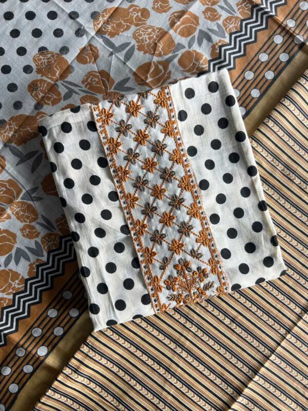 Unstitched Mal Mal cotton suit set with black polka dots, mustard floral embroidery, and matching printed fabrics, laid out on a table.