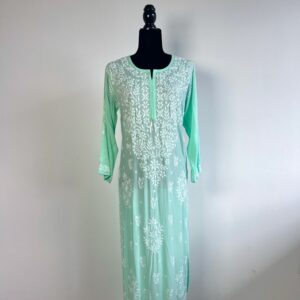 Black half-body mannequin displaying a pastel green chikankari kurti with intricate white embroidery, three-quarter sleeves, and a flowing design.