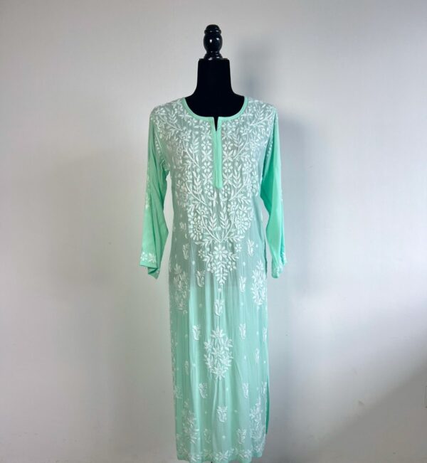 Black half-body mannequin displaying a pastel green chikankari kurti with intricate white embroidery, three-quarter sleeves, and a flowing design.