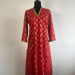 A scarlet long kurti with gold prints and embellished details, displayed on a black half-body mannequin against a white background.