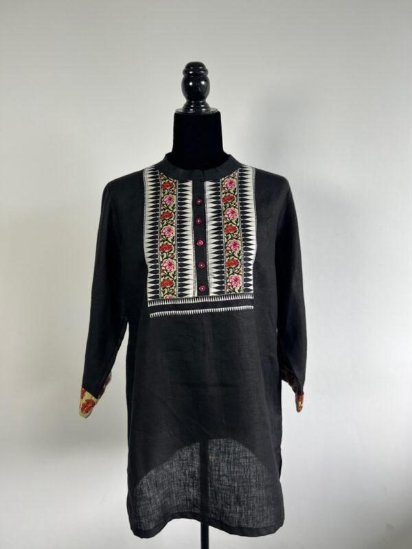 Black linen kurti on a mannequin with embroidered panel, red buttons, and contrast cuffs.