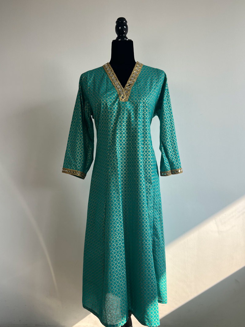 A teal long kurti with gold lattice prints and mirror-embellished details, displayed on a black half-body mannequin against a white background.