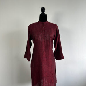 Maroon linen kurti on a mannequin, featuring pin-tuck yoke detailing, wooden buttons, and stitched accents.