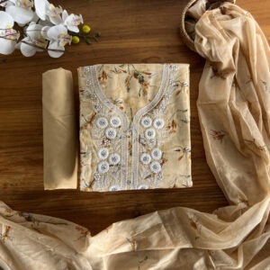 Unstitched cream floral top with embroidery, plain pant, and matching floral dupatta on a wooden background