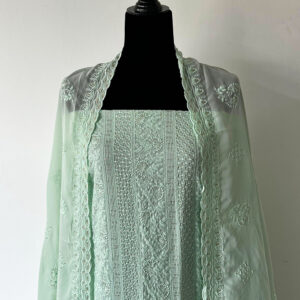 Unstitched 3-piece mint green material set with delicate embroidery, folded pant fabric, and matching sheer dupatta displayed on a wooden surface.