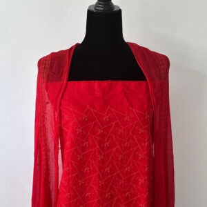 Red unstitched 3-piece set displayed on a black mannequin — featuring a geometric-embroidered kurta top and a sheer dupatta with thread detailing draped over the shoulders.
