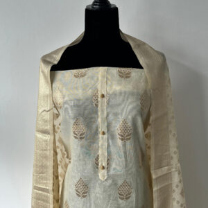 Cream unstitched 3-piece set displayed on a black mannequin, featuring woven motifs on the top and Banarasi-style dupatta draped over the shoulders.