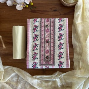 Unstitched 3-piece material set with cream floral printed top, plain yellow pant material, and striped sheer dupatta laid flat on a wooden table.