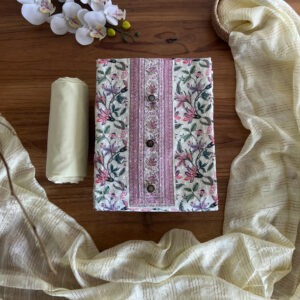 Unstitched 3-piece material set with cream floral printed top, plain matching pant fabric, and striped dupatta laid flat on a wooden table.