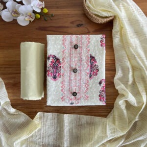 Unstitched 3-piece material set with cream floral printed top, plain pant fabric, and striped shimmer dupatta laid flat on a wooden table.
