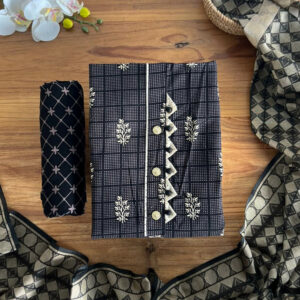 Black and gold unstitched 3-piece material set laid flat on a wooden surface, featuring kurta, pant material, and dupatta.